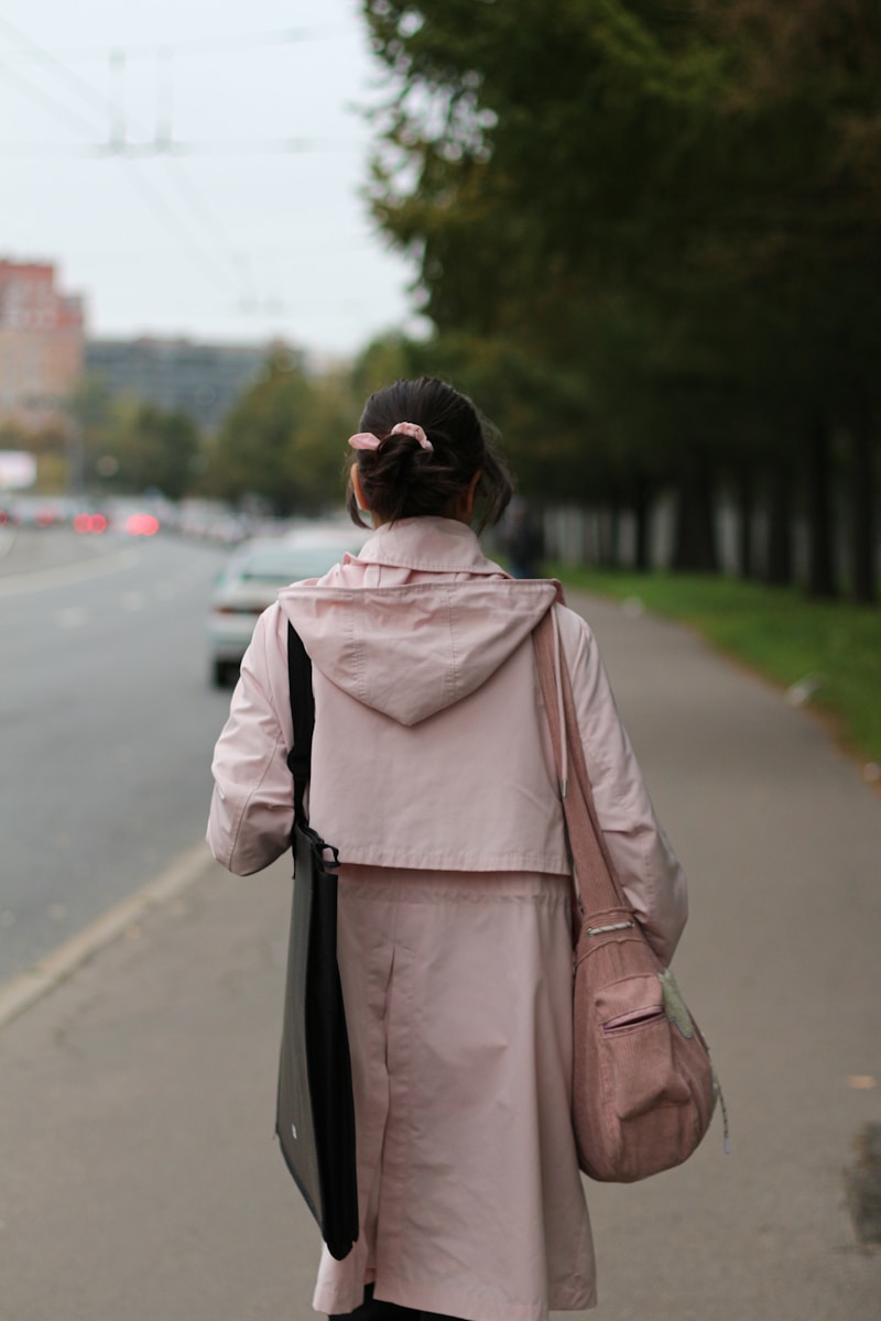 A woman in a pink coat is walking down the street